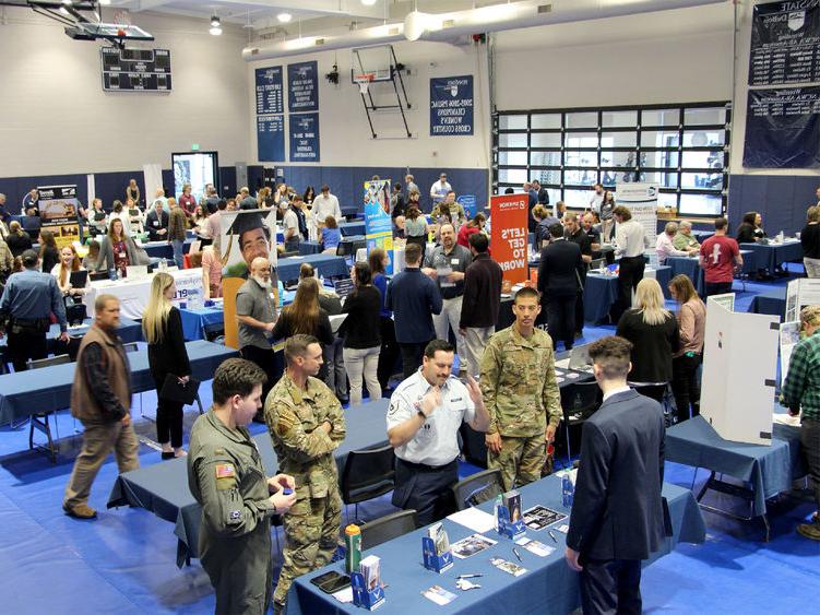 A full gym floor at the PAW Center, with the floor being full of employers, 学生, alumni and community members during the career fair.